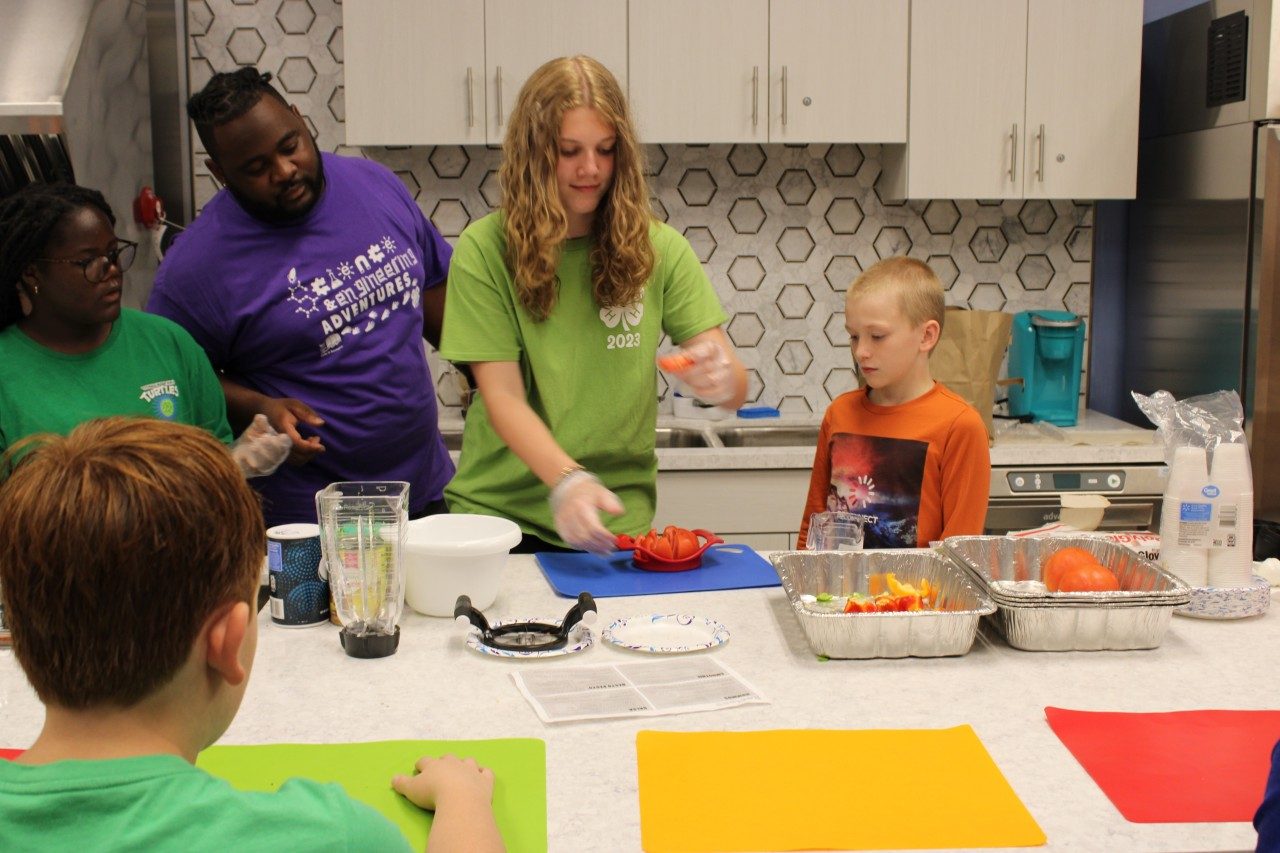 Volunteers assisting youth participants with food preparation at Science Camp